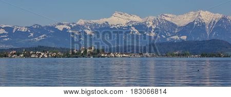 Rapperswil on a spring day. Medieval castle lake Zurichsee and snow capped mountain Grosser Speer.