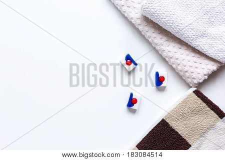 laundry set with pastel towels and detergent on white table background top view mockup