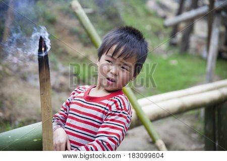 Sa Pa, Vietnam - 12 March, 2017: Ethnic minority, Hmong boy playing with the fire in tradition village of Cat cat, Sapa, Vietnam