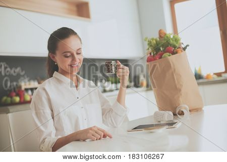 Young woman planning expenses and paying bills on her kitchen