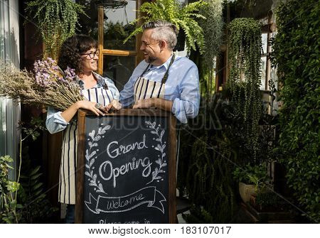 Adult Man and Woman Standing with Grand Opening Sign