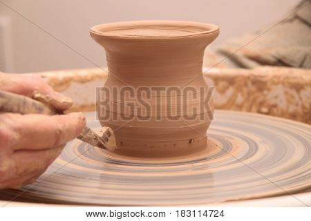 hands of a potter, creating an earthen jar on a pottery wheel