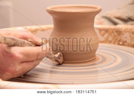 hands of a potter, creating an earthen jar on a pottery wheel