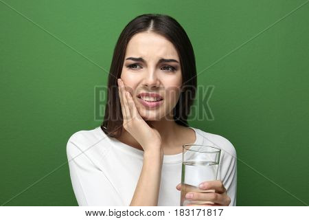 Beautiful young woman with medicine  suffering from toothache on color background