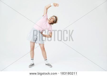 Full length portrait of man warming up before workout. Right hand up, looking up
