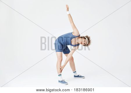 Nice guy bending at waist touching right leg with left hand. Fitness concept. White background