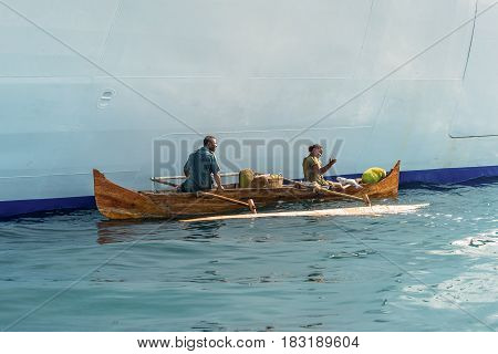 Hell-Ville Madagascar - December 19 2015: Malagasy vendors from their outrigger canoe offer fish and tropical fruits to ship passengers at Hell-Ville Nosy Be Island Madagascar.