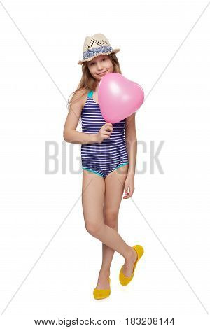 Full length child girl in swimsuit and summer hat with pink balloon heart shape, studio portrait