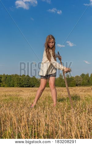 Teengirl with a scythe at summer field traditional countrywoman