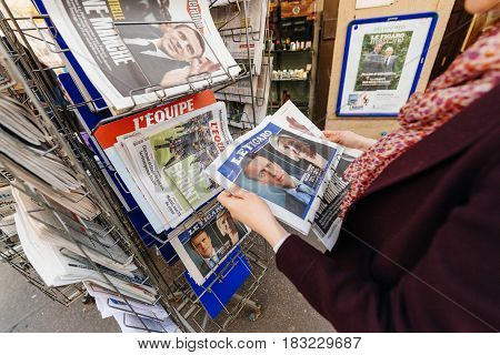 PARIS FRANCE - APRIL 24: Woman looks at press kiosk at French newspaper Le Figaro with pictures of French Presidential election candidates Emmanuel Macron Marine Le Pen a day after first round of French Presidential election on April 23 2017