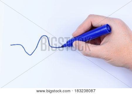 Hand holding a blue pen drawing a wavey line isolated on white background