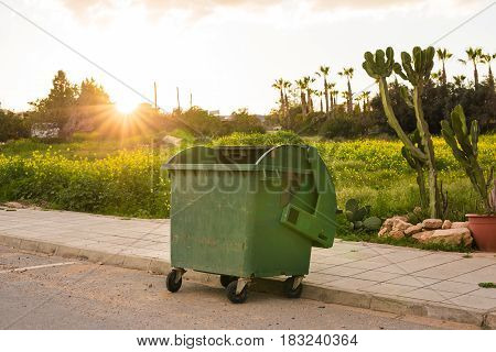 City trash cans. Green overfilled trash dumpster