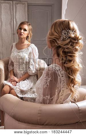 The Blond Haid Bride Sitting In White Dress Neat The Mirror