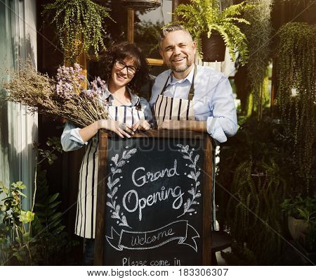 Adult Man and Woman Standing with Grand Opening Sign