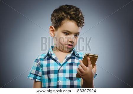 Portrait of happy boy with mobile going surprise on gray background.