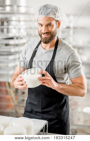 Handsome man in uniform enjoying the process of making cheese at the small producing farm