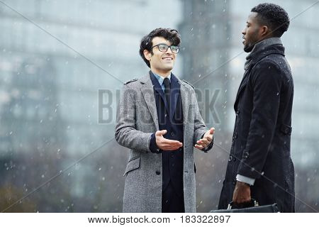 Intercultural businessmen having conversation on snowy weather