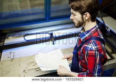 Worker of technical lab holding papers with sketches