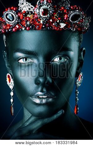 Jewelry industry. Fashion portrait of a beautiful young woman with perfect black skin wearing diadem with rubies and other precious stones. Jewelry and bijouterie. Body painting project.