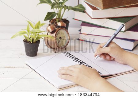 hand writing paper on desk and work place with clock book and palnt