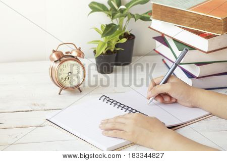 hand writing paper on desk and work place with clock book and palnt