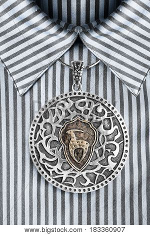 Vintage ethnic silver medallion over satin striped blue blouse closeup