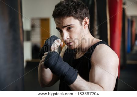 Close up view of a boxer training in gym with punchbag