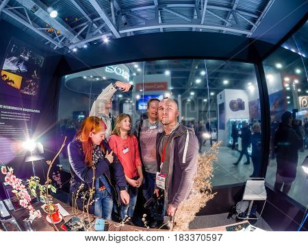 MOSCOW RUSSIA - APRIL 21 2017: Visitors take part in macro photography workshop at booth of Olympus company at PhotoForum 2017 trade show and exhibition in Moscow Russia on April 21 2017.