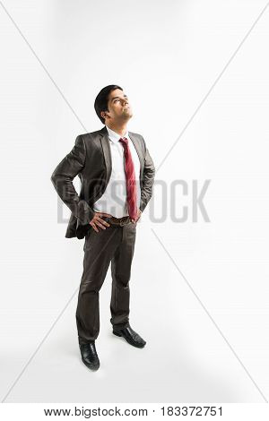 indian young & handsome businessman in clean shave and office wear standing, looking up / in the sky, a view from top also known as bird's eye view showing perspective, isolated over white background