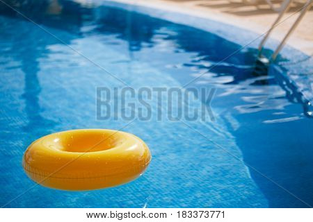 floating ring on blue water swimpool with waves reflecting in the summer sun