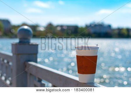 Coffee single cup on the fence The lake and the city in bokeh