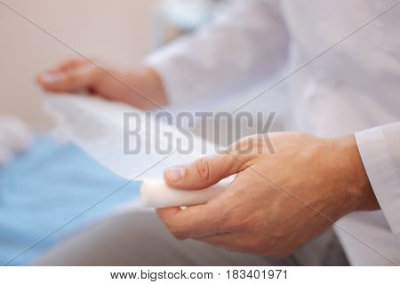 Serious injury. Close up of a bandage being used by a nice professional male rheumatologist while bandaging a wound