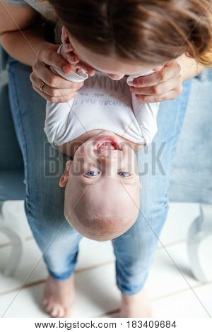 Newborn child lies on his mother's lap. Mother holding her newborn child. Woman and new born boy relax in a white bedroom. Mother breast feeding baby. Family at home