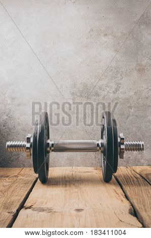 iron dumbbell on a wooden plank with gray background