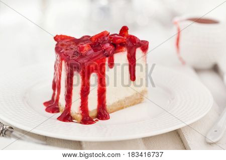 Delicious cheesecake decorated with berry sauce on white