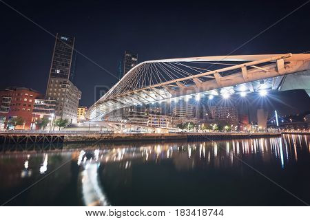 Bilbao cityscape and pedestrian zubizuri bridge at night Bilbao Basque country Spain.