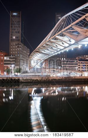 Bilbao cityscape and pedestrian zubizuri bridge at night Bilbao Basque country Spain.