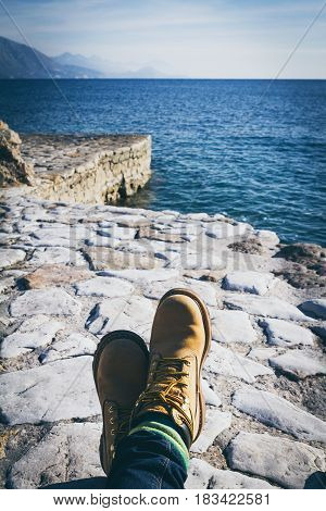 Ploce beach. Republic of Montenegro. Legs in yellow boots sea mountains and a puffy white clougs in the sky.