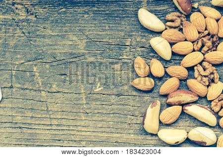 Concept - Nuts mix on old rustic wooden background with place for text. Almonds Brazil nuts and walnuts. Healthy edible seeds food ingredient on the table. Top view. Directly above. Copy space.