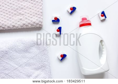 laundry set with pastel towels and detergent plastic bottel on white table background top view