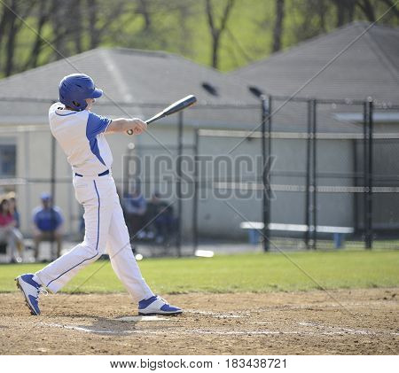 teenage high school baseball batter swinging at a ball