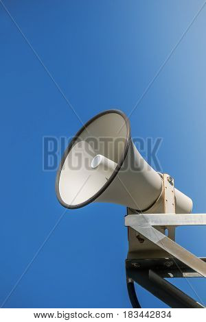 Horn speaker white metal on blue sky background.