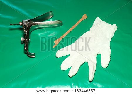 Colposcop spatula and Medical gloves on a clean green blanket (Equipment vaginal speculum) for (Pap smear) gynecology inspect EXAMINATION Cervical cancer