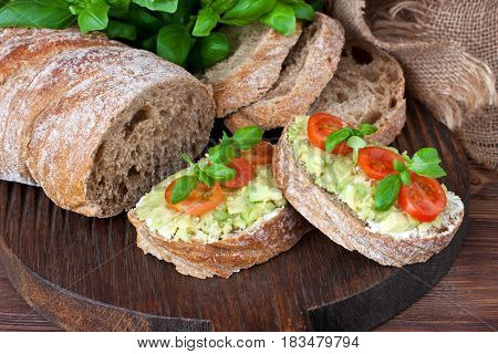 Freshly baked traditional ciabatta bread  with  avocado cream  on wooden board