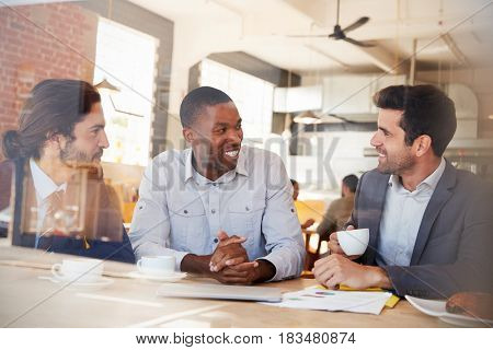 Three Businessmen Meeting In Coffee Shop Shot Through Window