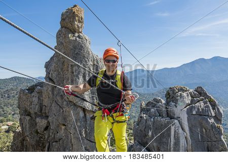 Male climber wearing special clothing and walking on rope with landscape on background