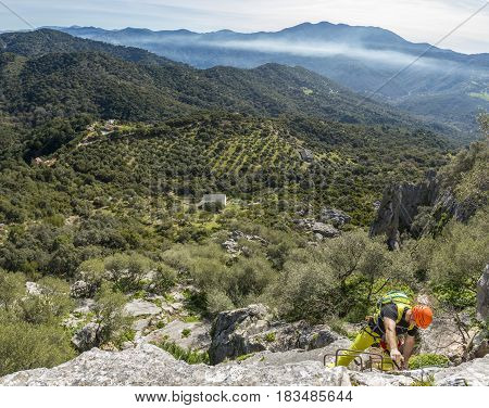 From above shot of man in special clothing climbing up with help of mountaineering equipment