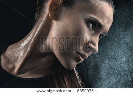 Close-up Portrait Of Young Sweaty Fitness Woman Looking Away On Black