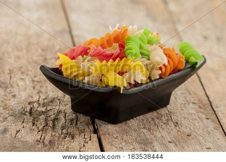 Assortment of colorful pasta in white bowls on wooden background