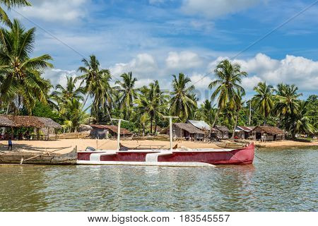 Ambatozavavy Nosy Be Madagascar - December 19 2015: Traditional wood pirogue and a modern boat with outrigger on the shore of the fishing village on the Nosy Be island Madagascar.